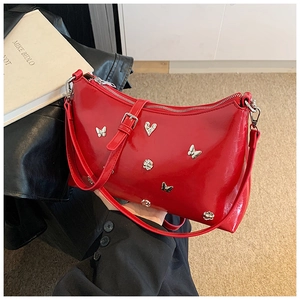 Détail du sac à main rouge brillant en cuir verni avec charmes en relief papillon argenté