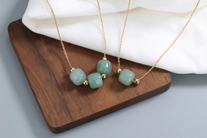 Detail of Hetian jade beads and gold chain necklaces on a wooden display stand