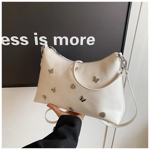 Détail du sac cabas crème avec clous papillon argentés et cuir synthétique texturé