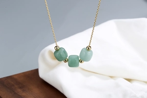 Macro view of three green jade beads on a delicate gold-plated s925 silver chain necklace