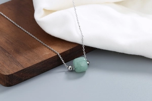 Detailed close-up of a square Hetian jade pendant necklace on a textured wood surface