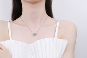 Close-up of a Hetian jade bead pendant on a silver necklace worn by a model