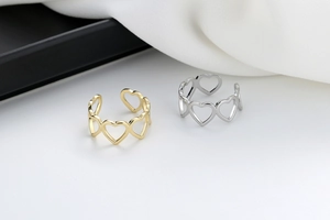 Detailed view of hollow heart patterns on adjustable gold and silver rings