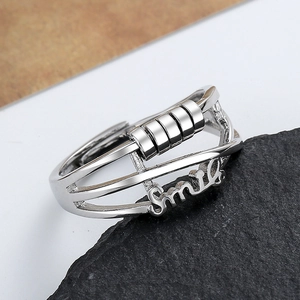 Silver rotating bead fidget ring with Smile engraving on a textured stone base