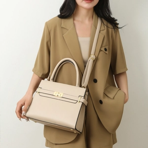 Sac à main trapèze beige classique en cuir texturé avec fermoir doré porté par un modèle