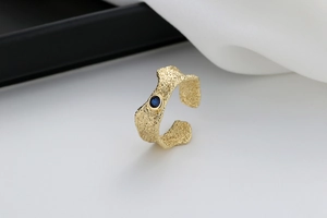 Detailed view of irregular gold ring featuring rock texture and a blue zircon stone