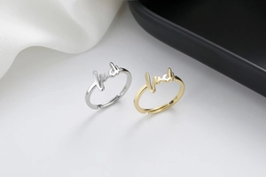 Detail of adjustable open rings in gold and silver with cursive luck lettering
