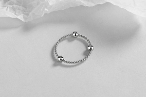 Detailed macro view of S925 sterling silver twisted rope ring with three polished beads