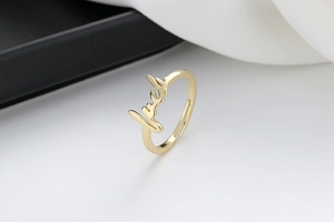 Macro shot of 18K gold plated adjustable lucky script letter open ring on contrast background