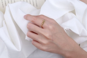 Detail of twisted gold ring with three rotating beads on a minimalist background