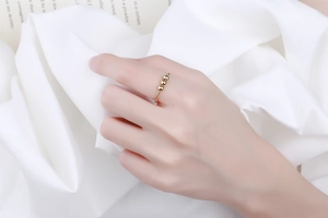 Detail of twisted gold ring featuring three polished beads on a female model hand