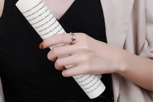 Detail shot of a silver adjustable ring featuring a lucky script design on a model