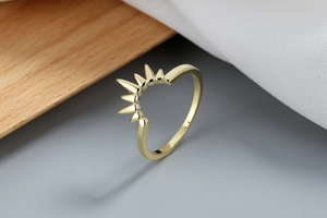 Dettaglio dell'anello a corona dorato con design a raggiera su sfondo in legno