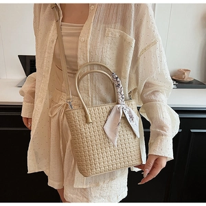 Detail of cream woven handbag with silk scarf handle and geometric braided texture