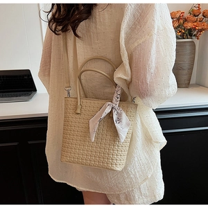 Detail of beige woven tote bag with floral silk scarf accessory and slim shoulder strap