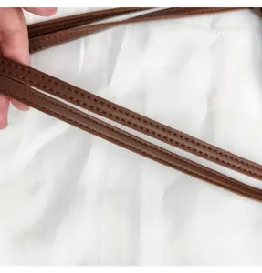 Detail of a brown leather shoulder strap with visible stitching and smooth texture