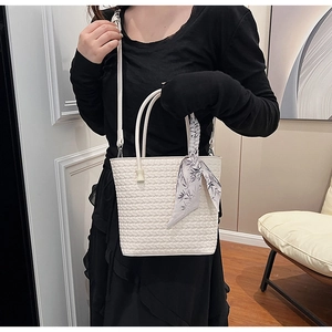 Detail of white woven textured tote bag with decorative floral silk scarf and long strap