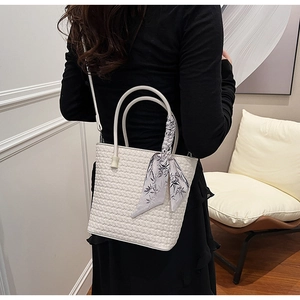 Detail of white woven bucket bag with floral silk scarf handle and adjustable strap