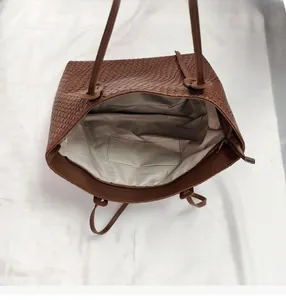 Detailed interior of a brown woven tote bag showing large capacity and inner pocket