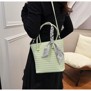 Detail of light green woven bucket bag with silk scarf handle and slim shoulder strap