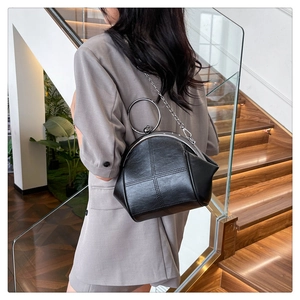 Detail of vintage black crossbody shell bag with metal frame and round handle clasp