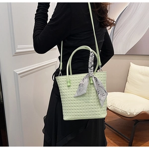 Detail of pale green woven bucket bag featuring an elegant scarf wrap and slim shoulder strap