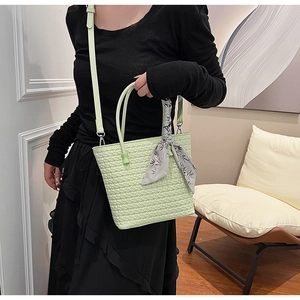 Close-up of light green woven tote bag featuring a floral silk scarf and elegant texture