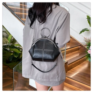 Detail of vintage black shell bag with white cross stitching and metal ring handle