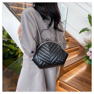 Lifestyle shot of black quilted shell bag with silver ring handle and chain strap