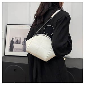White leather shell bag with round silver handle and chain strap on a model shoulder