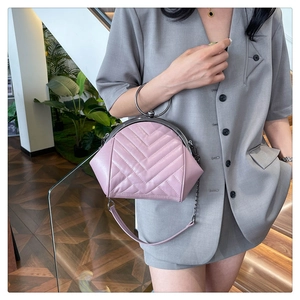 Detailed side view of pink quilted shell bag with silver ring handle on model