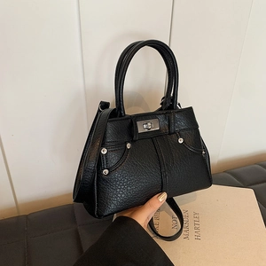 Classic black faux leather handbag with silver twist lock and rivets in a lifestyle setting