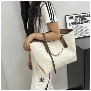 Close-up of woven white tote bag with contrast brown straps and detailed texture