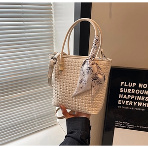 Detail of white woven leather handbag featuring printed silk scarf wrap on top handle