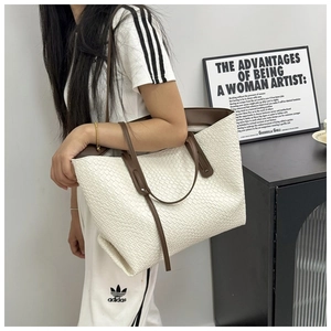 Detail of woven tote bag featuring white texture and dark brown leather shoulder straps