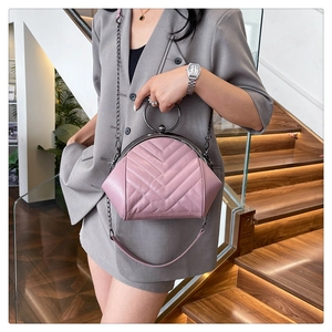 Pink quilted shell bag featuring a V-shaped stitch pattern and large black metal handle