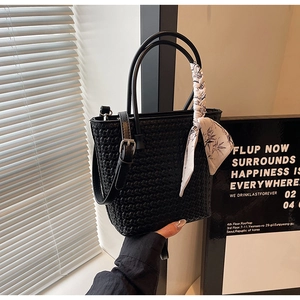 Close-up of black woven bucket bag with patterned silk scarf and leather shoulder strap