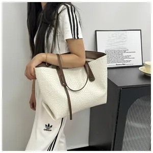 Detail of white woven tote bag featuring contrasting brown leather shoulder straps