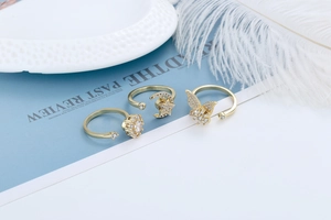 Detailed view of three gold butterfly and star zircon rings set on elegant props