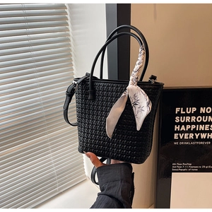 Detail of black woven bucket bag with elegant bamboo print silk scarf on the handle