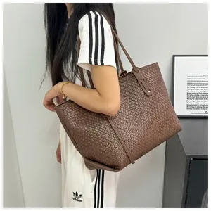 Detailed view of brown woven leather tote bag with long straps on a model shoulder