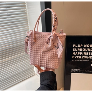 Detail of pink woven bucket bag featuring silk scarf handle and silver hardware