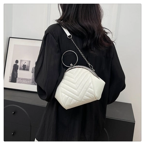 Detailed view of white quilted crossbody bag with vintage clasp and silver chain strap
