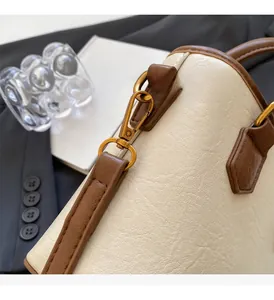 Détail du cuir texturé litchi et des ferrures en bronze antique sur le sac seau blanc