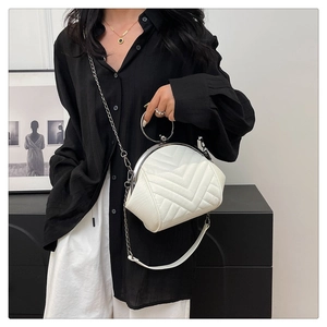Detail of white quilted shell bag showing metallic ring handle and silver chain strap