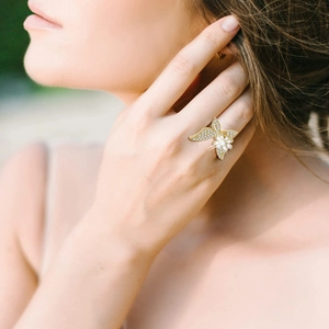 Detailed view of luxury gold butterfly ring with micro-pave zircons on model finger
