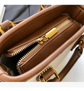 Détail de la fermeture éclair dorée et texture du cuir sur un sac seau bicolore