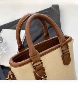 Détails du sac seau crème avec poignées en cuir marron et chaîne métallique dorée