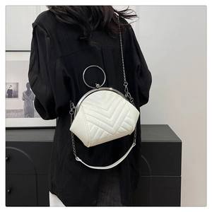 Close-up of white chevron quilted bag with silver ring handle and kiss-lock closure