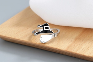 Macro shot of silver witch hat and broom ring detail on rustic wood surface
